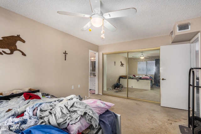 carpeted bedroom with ceiling fan, a closet, and a textured ceiling