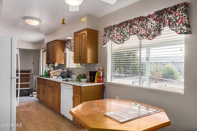 kitchen with white appliances, plenty of natural light, and light wood-type flooring