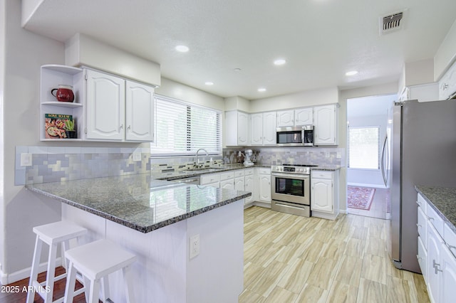 3921 W Jasper Dr, Chandler, AZ 85226 - kitchen featuring stainless steel appliances, a peninsula, dark stone countertops, white cabinets, and backsplash