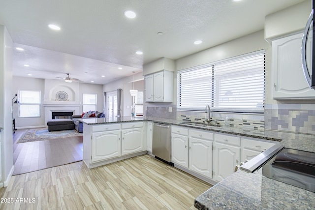 3921 W Jasper Dr, Chandler, AZ 85226 - kitchen with stainless steel dishwasher, a sink, a peninsula, ceiling fan, and a fireplace