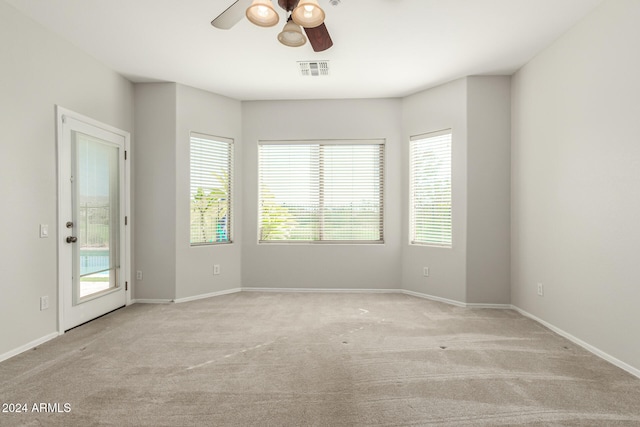 carpeted spare room with visible vents, plenty of natural light, baseboards, and ceiling fan