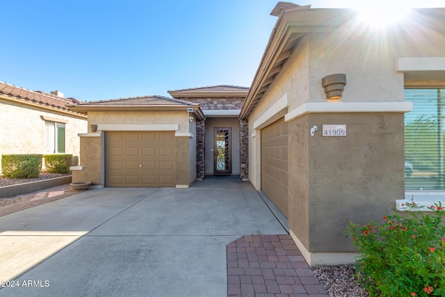 view of front facade featuring a garage, stone siding, driveway, and stucco siding