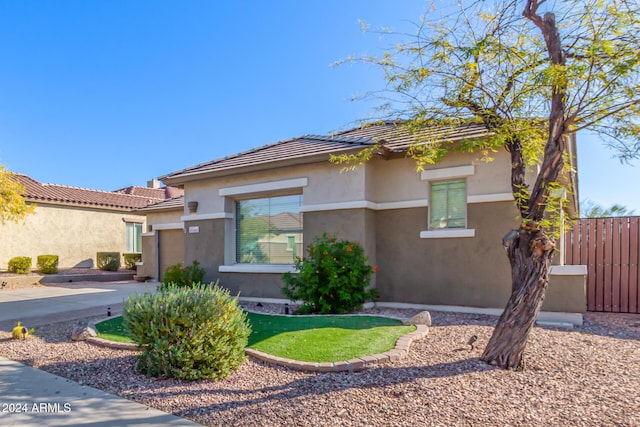 view of front of house with a garage, concrete driveway, fence, and stucco siding