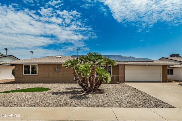 ranch-style home with a garage and solar panels