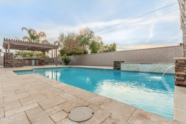 view of pool featuring a pergola, a patio area, pool water feature, and an outdoor kitchen