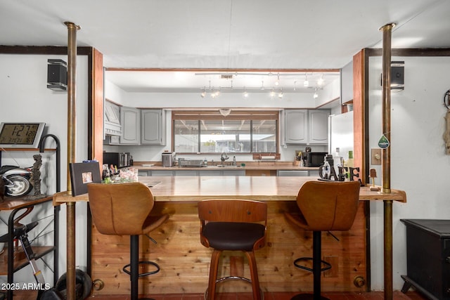 kitchen with gray cabinets, sink, and a kitchen breakfast bar