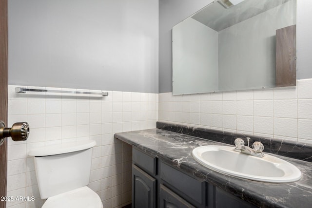 bathroom with vanity, toilet, and tile walls