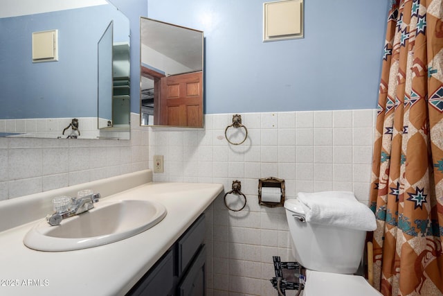 bathroom featuring vanity, tile walls, and toilet