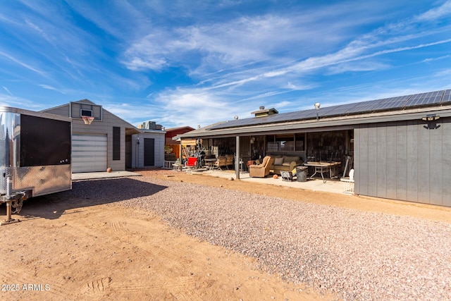 rear view of house with an outdoor living space, a garage, a patio area, and solar panels