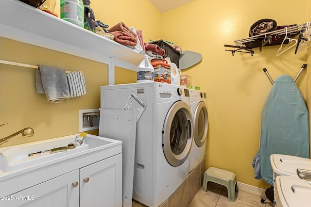 laundry room featuring sink, light tile patterned floors, cabinets, and independent washer and dryer