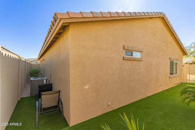 view of side of home with central air condition unit and a lawn