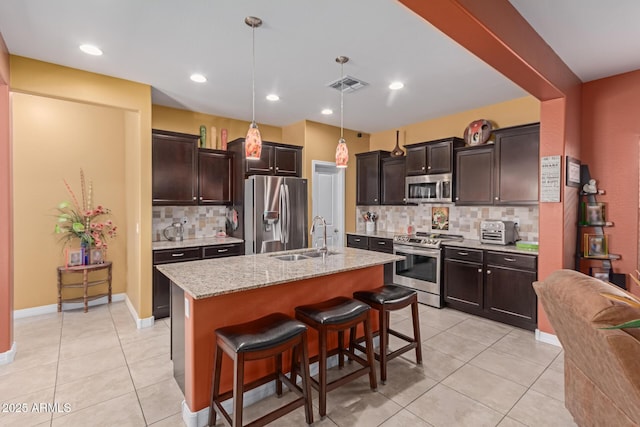 kitchen with a breakfast bar, decorative backsplash, a kitchen island with sink, appliances with stainless steel finishes, and sink