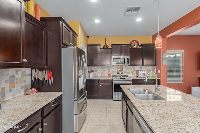 kitchen featuring appliances with stainless steel finishes, pendant lighting, backsplash, and sink