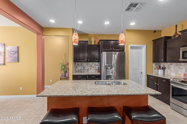 kitchen with stainless steel appliances, pendant lighting, and an island with sink