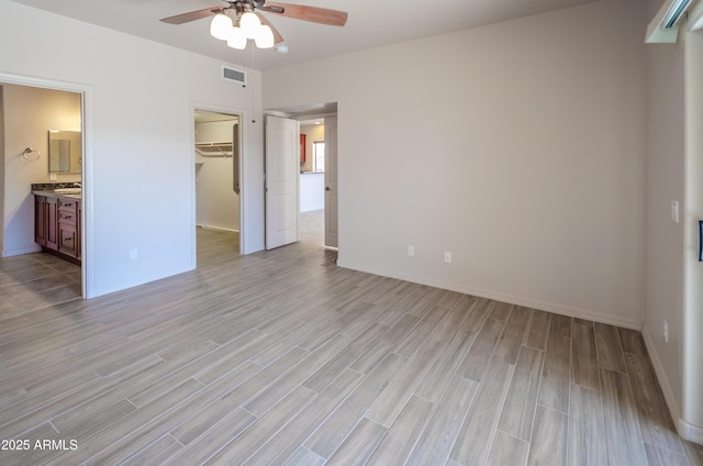 unfurnished bedroom with baseboards, visible vents, a spacious closet, light wood-type flooring, and a closet