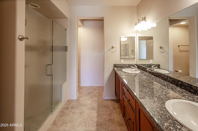 full bath with double vanity, a stall shower, baseboards, and a sink