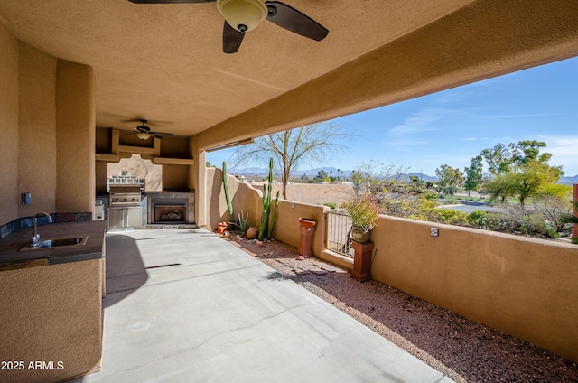 view of patio featuring fence private yard, a sink, an outdoor kitchen, and ceiling fan