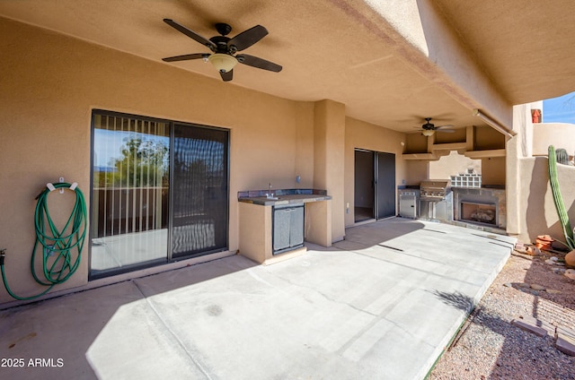 view of patio with ceiling fan, an outdoor kitchen, and an outdoor fireplace