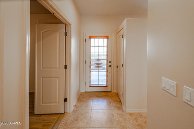 doorway with light tile patterned floors and baseboards