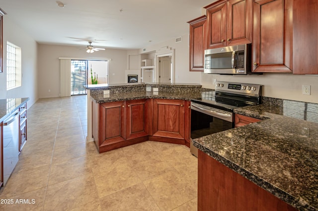 kitchen featuring dark stone counters, ceiling fan, appliances with stainless steel finishes, open floor plan, and a peninsula