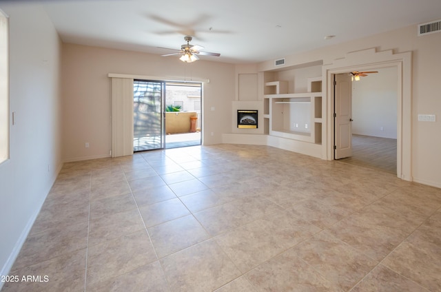 unfurnished living room featuring ceiling fan, light tile patterned floors, visible vents, baseboards, and a glass covered fireplace