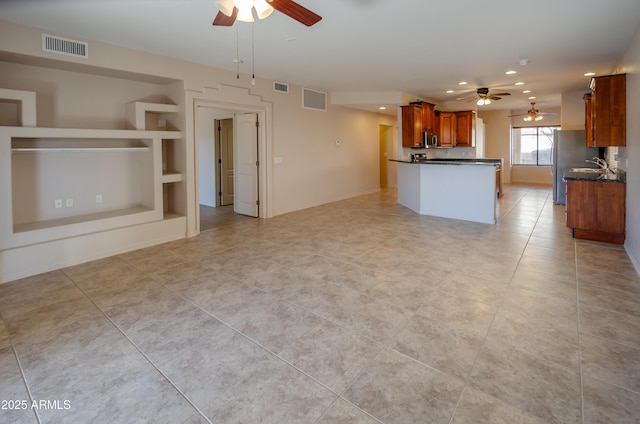 kitchen featuring brown cabinets, dark countertops, open floor plan, and visible vents