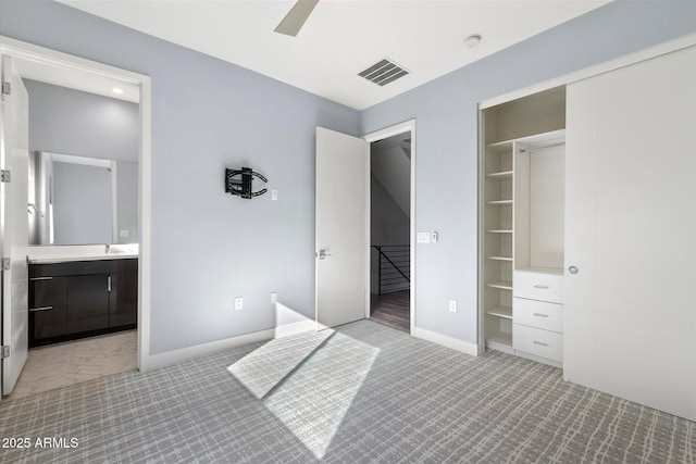 unfurnished bedroom featuring ensuite bath, a closet, ceiling fan, and light colored carpet