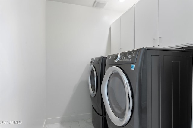 washroom with washer and dryer and cabinets