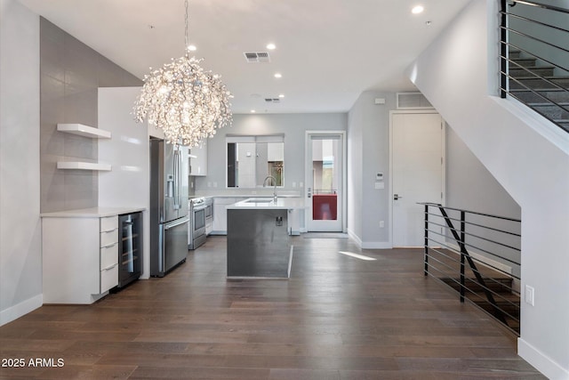 kitchen featuring appliances with stainless steel finishes, a notable chandelier, pendant lighting, dark wood-type flooring, and sink