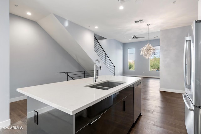 kitchen featuring sink, dark wood-type flooring, a spacious island, ceiling fan with notable chandelier, and appliances with stainless steel finishes