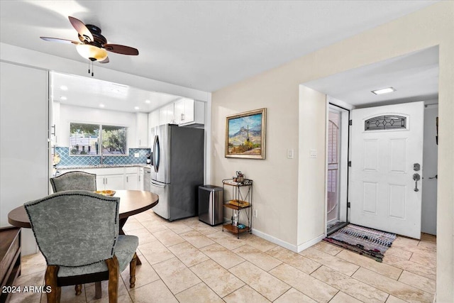 kitchen featuring light tile patterned flooring, white cabinetry, tasteful backsplash, stainless steel refrigerator with ice dispenser, and ceiling fan