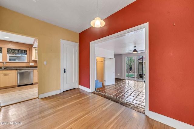 unfurnished dining area with a sink, baseboards, light wood finished floors, and ceiling fan