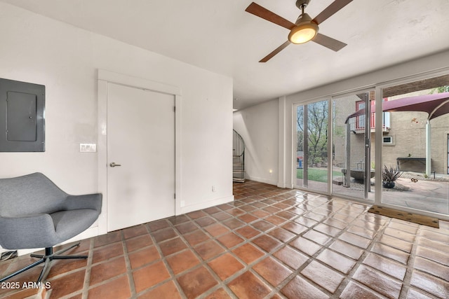 unfurnished living room featuring electric panel, a ceiling fan, and baseboards
