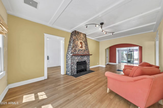 living room featuring arched walkways, baseboards, a fireplace, and wood finished floors