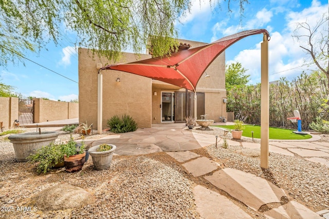rear view of property featuring stucco siding, a patio, and fence