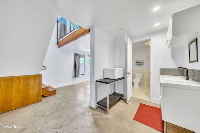 bathroom with concrete floors, toilet, vanity, and recessed lighting