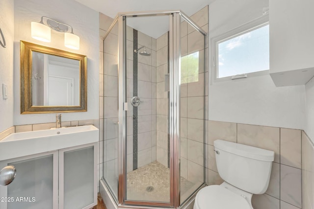 full bathroom with a shower stall, toilet, vanity, and tile walls