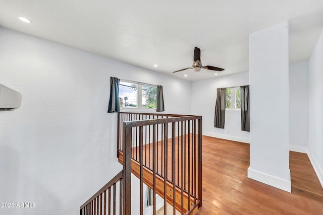 hallway with an upstairs landing, wood finished floors, recessed lighting, baseboards, and a wall unit AC