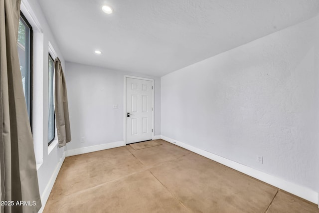 empty room with baseboards, concrete flooring, and recessed lighting