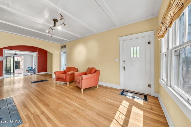 entryway featuring arched walkways, light wood finished floors, and baseboards