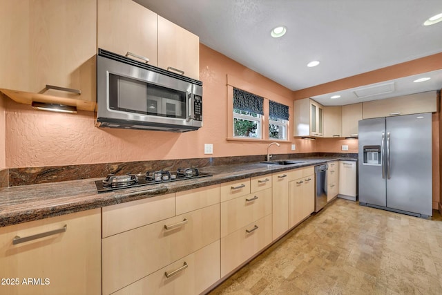 kitchen with stainless steel appliances, a sink, a textured wall, and recessed lighting