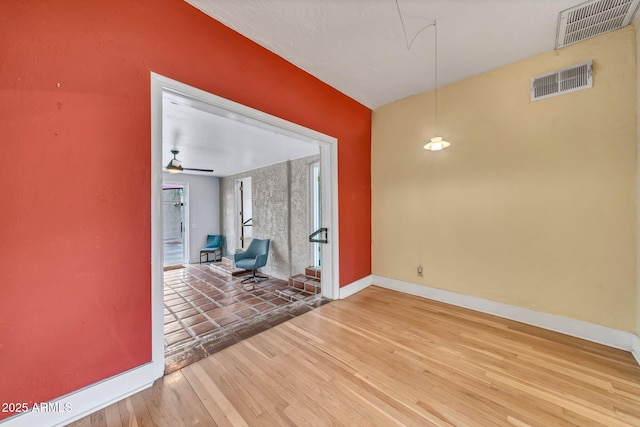 spare room featuring wood finished floors, baseboards, and a ceiling fan