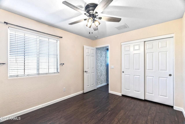 unfurnished bedroom with ceiling fan, dark hardwood / wood-style floors, a closet, and multiple windows