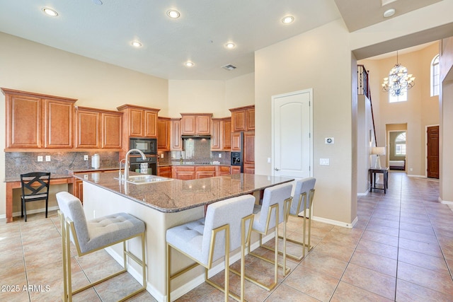 795 W Verbena Ln, Litchfield Park, AZ 85340 - kitchen with a high ceiling, a sink, brown cabinets, light tile patterned flooring, and a breakfast bar area