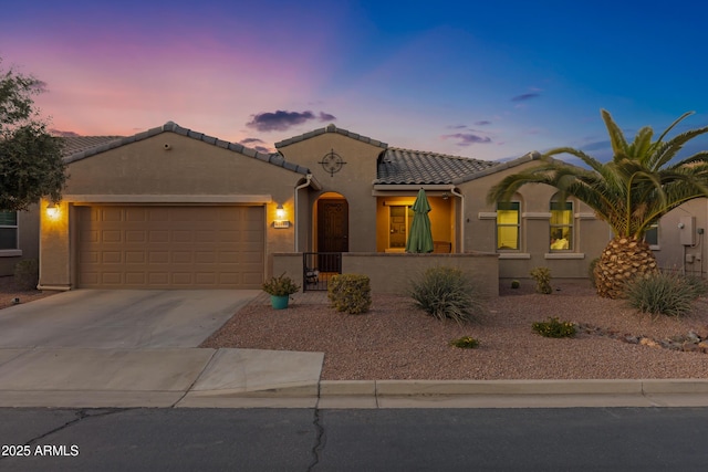 mediterranean / spanish-style home with a garage, concrete driveway, a tile roof, and stucco siding