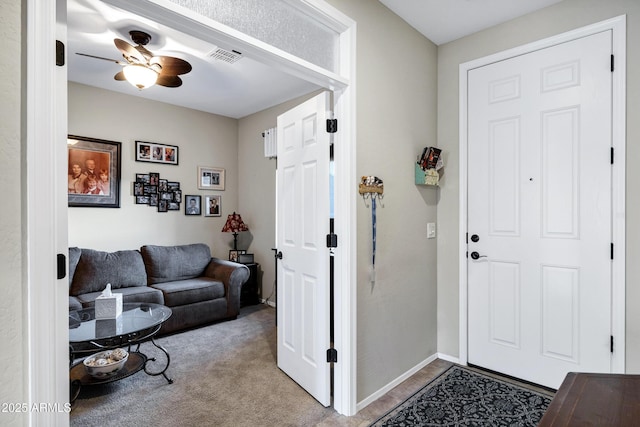 carpeted entrance foyer featuring ceiling fan, visible vents, and baseboards