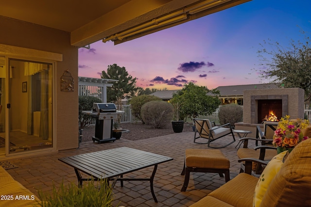 view of patio featuring a warm lit fireplace, a pergola, a grill, and fence