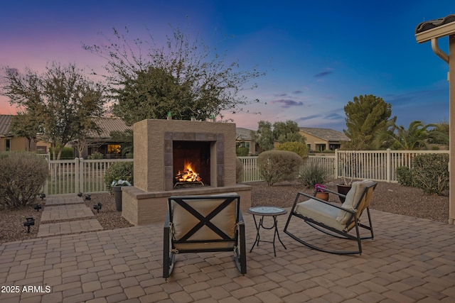 view of patio / terrace with a lit fireplace and fence