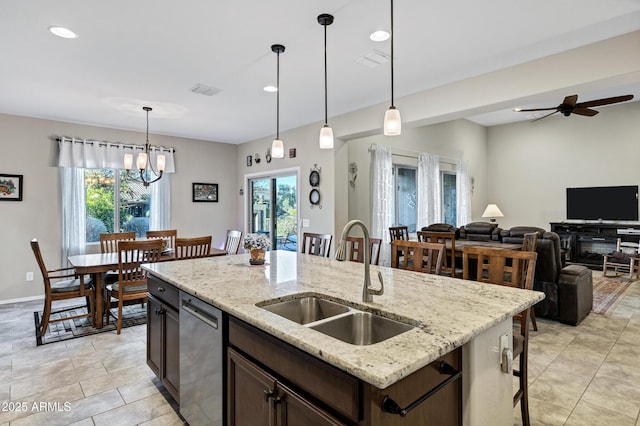 kitchen with decorative light fixtures, stainless steel dishwasher, a healthy amount of sunlight, a sink, and dark brown cabinets