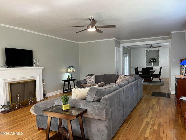 living room with wood-type flooring, ornamental molding, and ceiling fan